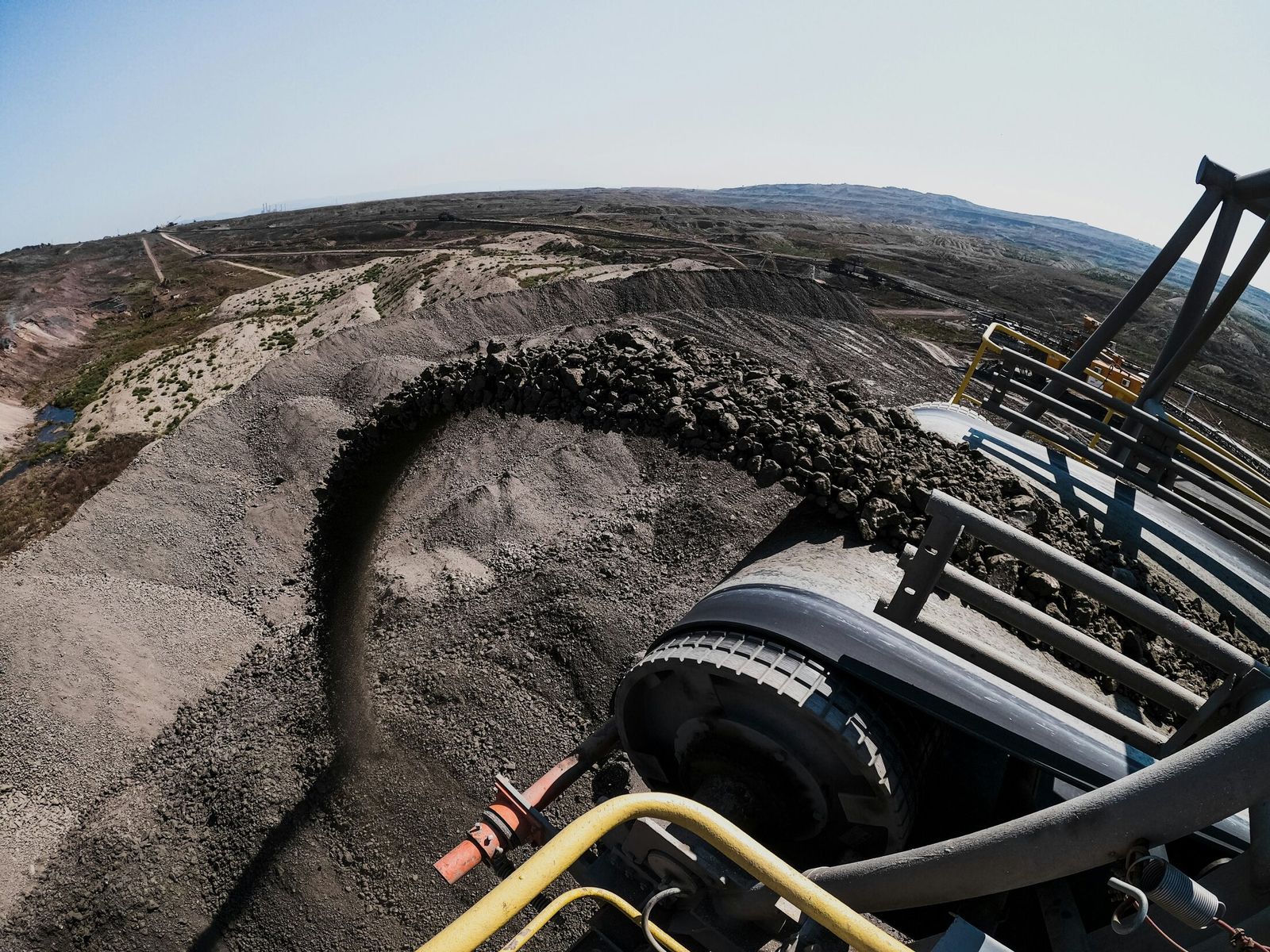 Industrial conveyor system carrying ore across an open-pit mine ridge