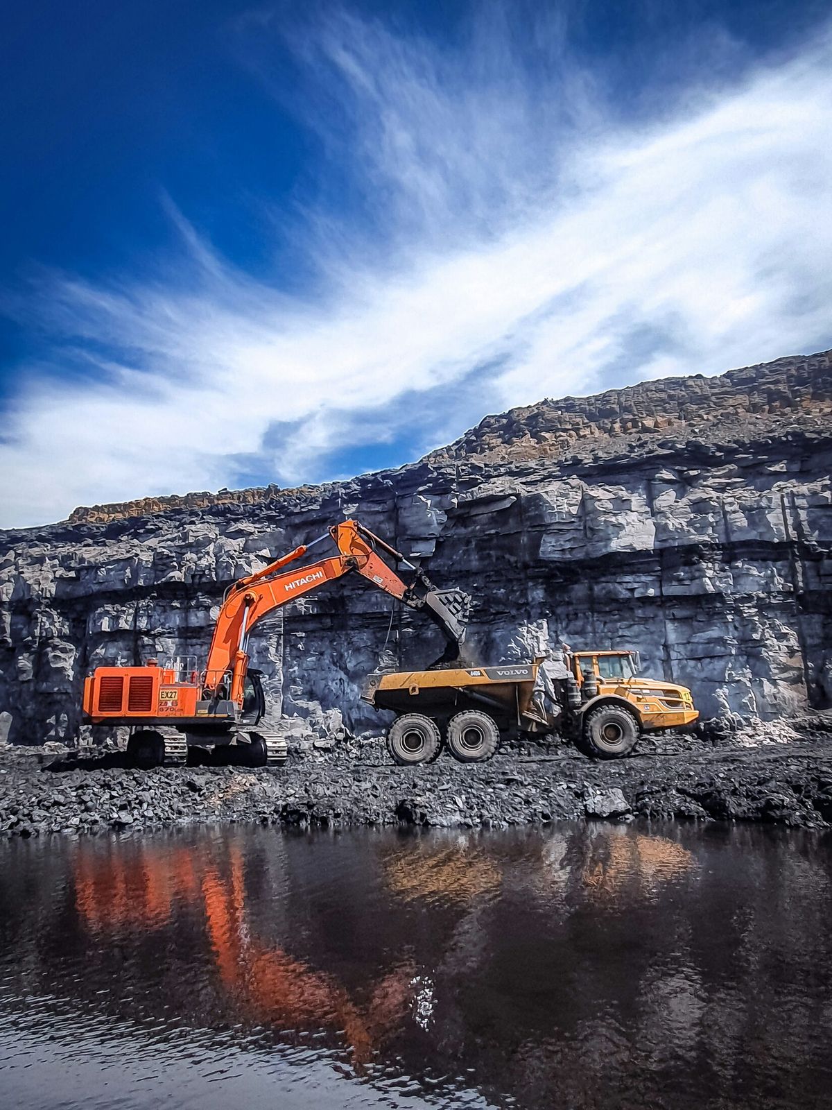 Excavator loading ore into a haul truck at an open quarry